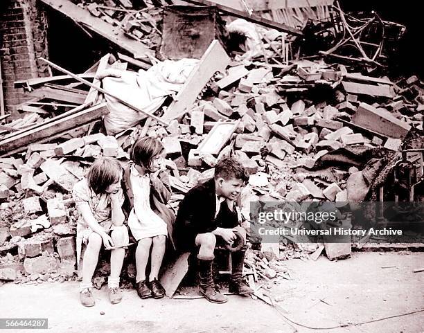 Homeless children sit in front of their wrecked home, in London's East End during the blitz of World War Two 1940.