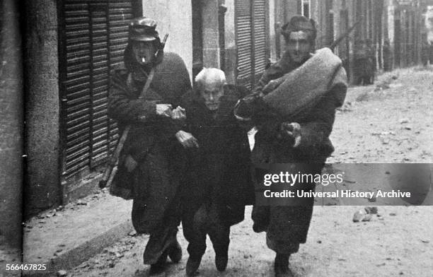 Civilian is helped to safety at Teruel, during the Spanish Civil War. The combatants fought the battle between December 1937 and February 1938,...