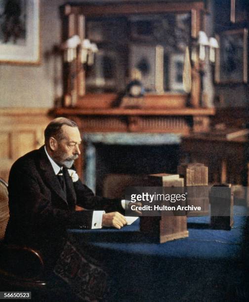 King George V of Great Britain preparing to give a radio broadcast from a room at Sandringham House, circa 1933.
