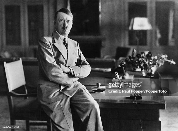 Nazi leader Adolf Hitler , sitting on the edge of a desk at his Berghof residence, Berchtesgaden, Bavaria, Germany, during World War II, circa 1940.