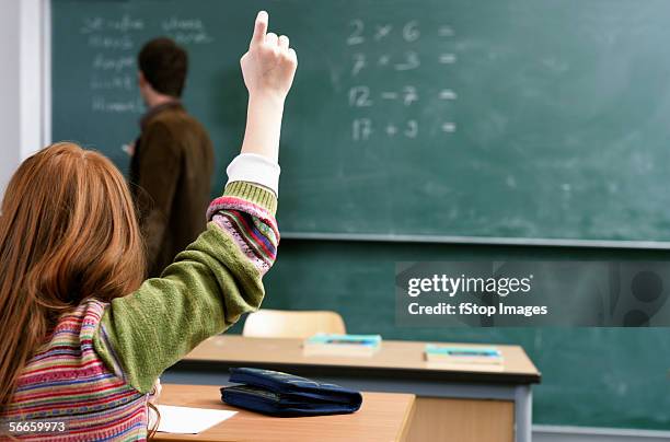 rear view of a girl raising her hand in a classroom - blackboard classroom stock-fotos und bilder