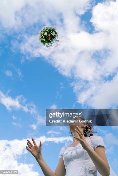 low angle view of a bride tossing a bouquet of flowers - bouquet toss stock pictures, royalty-free photos & images