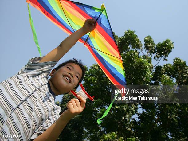 low angle view of a boy holding a kite - tee reel stock pictures, royalty-free photos & images