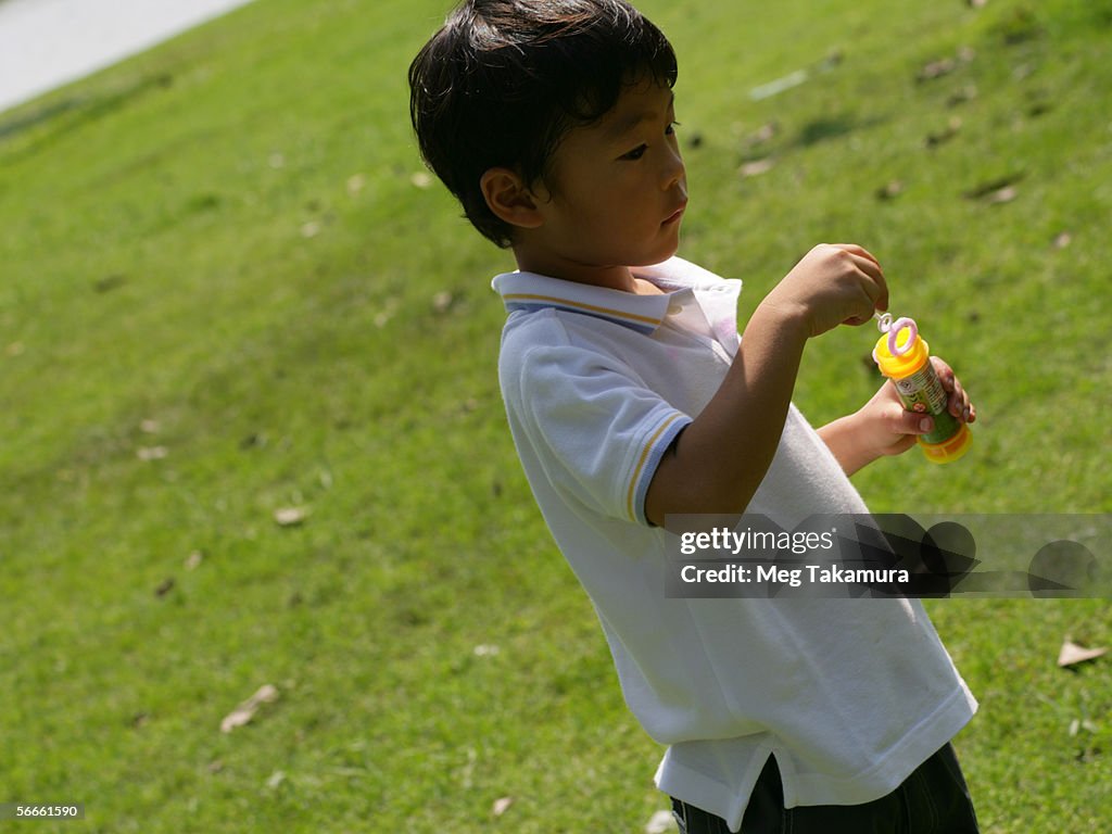 Side profile of a boy blowing bubbles with a bubble wand