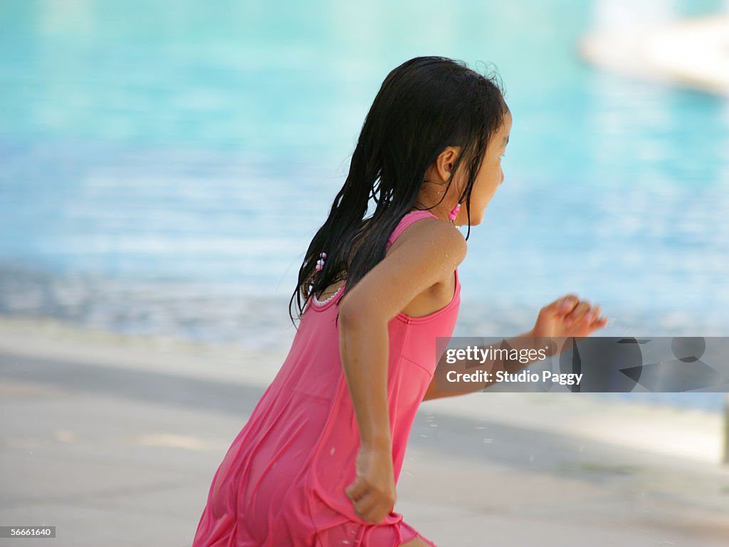 Side profile of a girl running towards a swimming pool