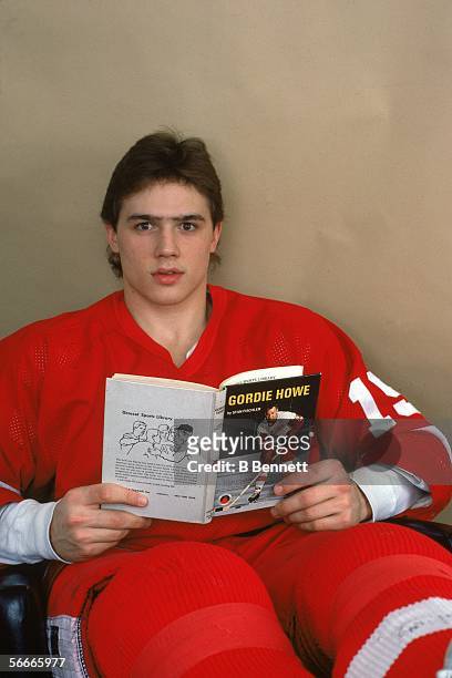 Candian professional hockey Steve Yzerman, center for the Detroit Red Wings, poses holding an open book about Canadian hockey player Gordie Howe,...