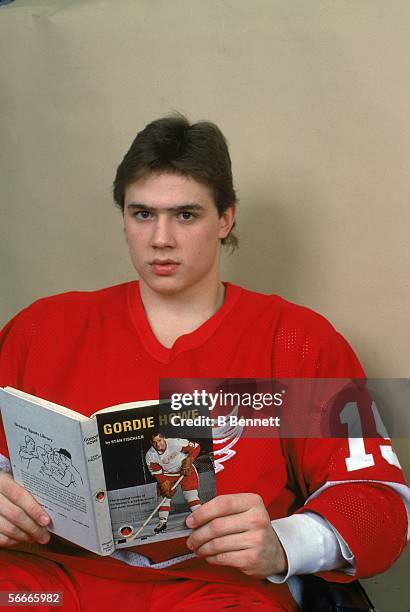 Candian professional hockey Steve Yzerman, center for the Detroit Red Wings, poses holding an open book about Canadian hockey player Gordie Howe,...