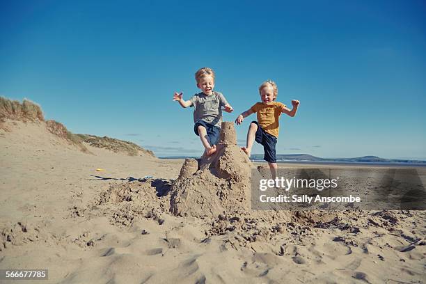 children jumping on a giant sandcastle - sand castle stock pictures, royalty-free photos & images