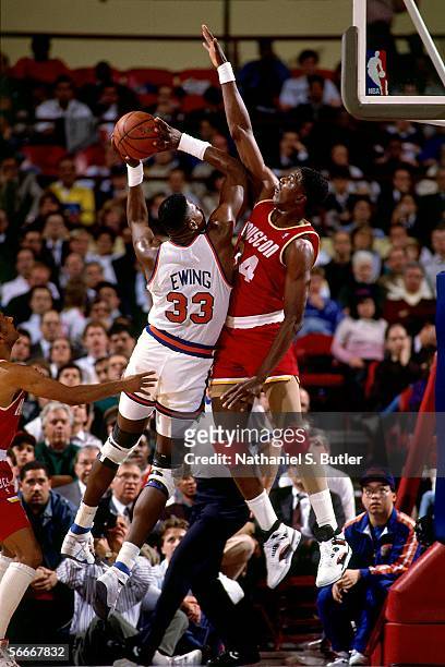 Patrick Ewing of the New York Knicks shoots over Hakeem Olajuwon of the Houston Rockets circa 1990 at Madison Square Garden in New York, New York....