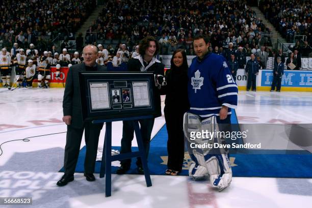 Ed Belfour of the Toronto Maple Leafs stands at center ice with wife Ashli, son Dayn and their dog Sunny, as former Maple Leaf Johnny Bower presents...