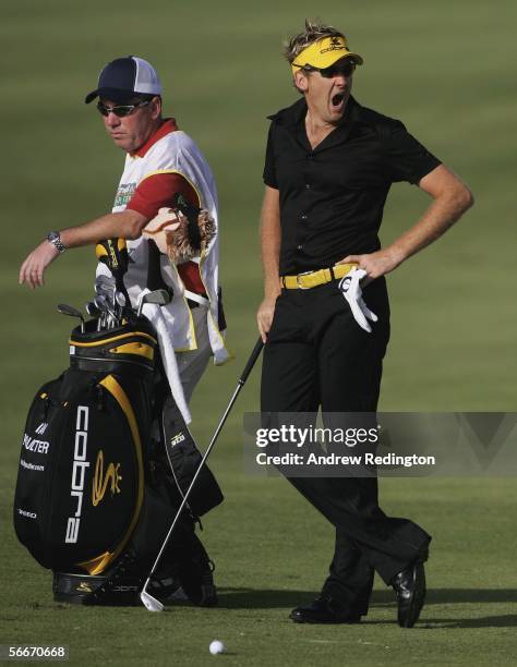 Ian Poulter of England yawns on the 15th hole as his caddie Mick Donaghy looks on during the first round of The Commercial Bank Qatar Masters at Doha...