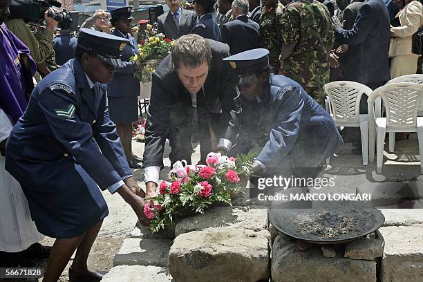 British High Commissioner in Kenya Adam Wood is helped by two Kenyan Air Force female soldiers to lay a wreath 26 January 2006 during a commemoration...