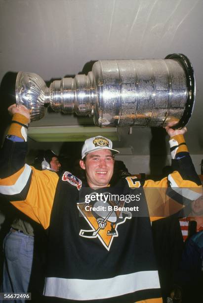 Canadian professional hockey player Mario Lemieux, forward for the Pittsburgh Penguins, hoists the Stanley Cup over his head as the Pens celebrate...