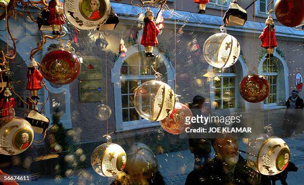 Tourists look at a shop display, offering Christmas decorations with Mozart's motiv on the eve of the birthday of famous composer Wolfgang Amadeus...