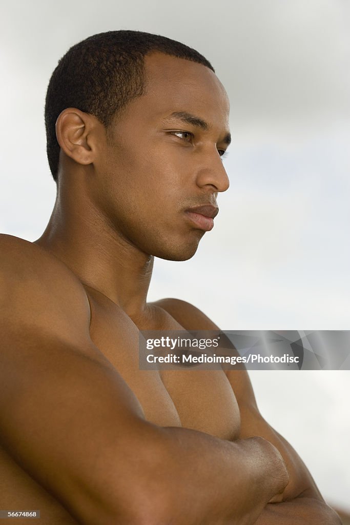 Side profile of a young man with his arms crossed