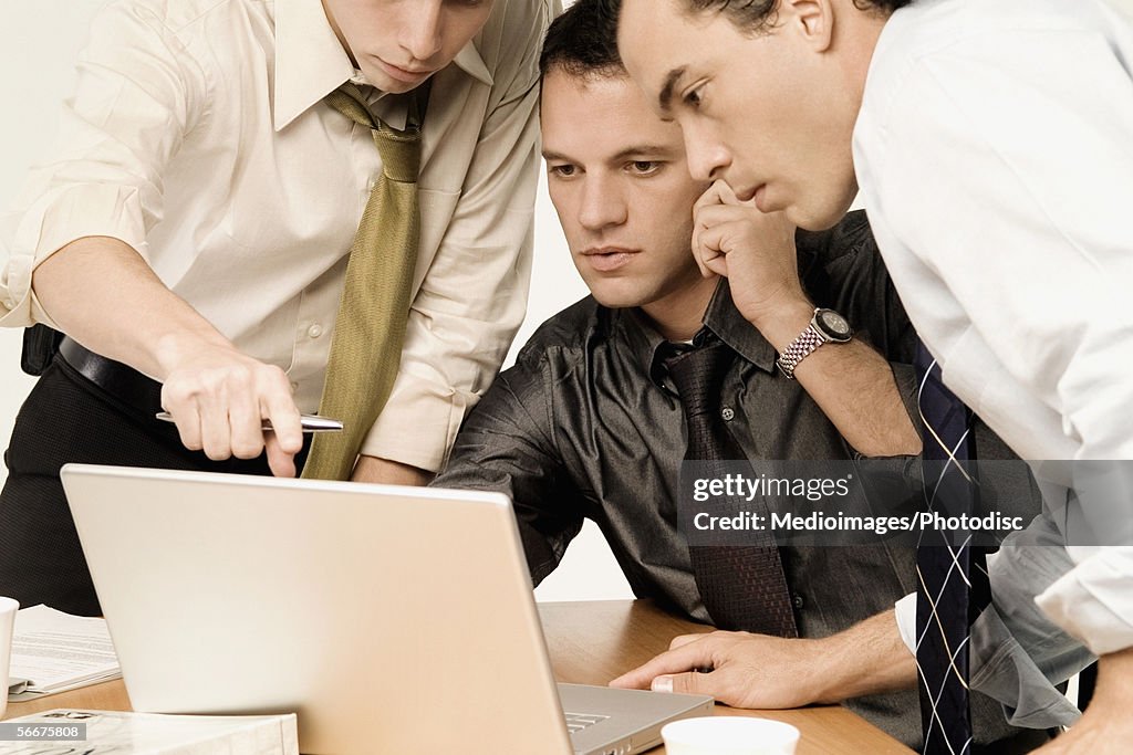 Three businessmen working on a laptop