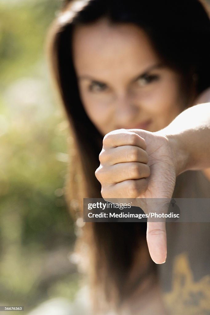 Portrait of a young woman showing a thumbs down sign