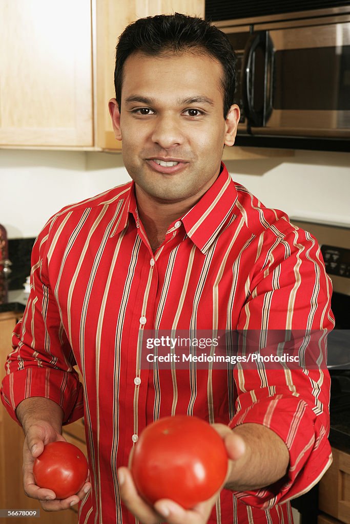 Portrait of a young man showing tomatoes