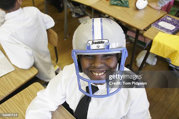 Fifth grade student Anthony Ward wears a Detroit Lions football helmet autographed by Lion players, Cory Schlesinger and Jeff Backus at the Malcolm X...