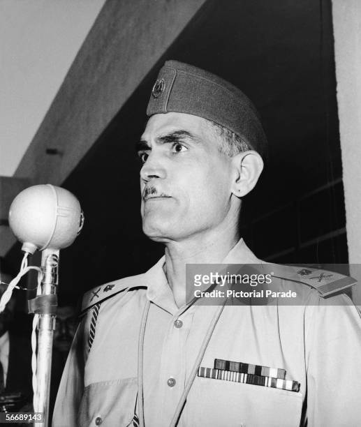 Iraqi Prime Minister and military officer General Abdul Karim Qassim , dressed in a military uniform, stands in front of a microphone and delivers a...