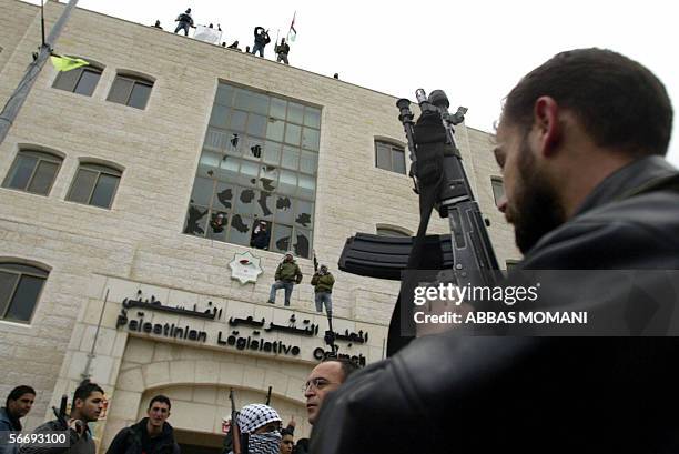 Palestinian Fatah members tot their rifles as gunmen erect a Palestinian flag and a Fatah banner on the Palestinian Legislative Council building, 28...