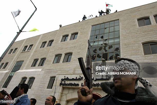 Palestinian Fatah members tot their rifles as gunmen erect a Palestinian flag and a Fatah banner on the Palestinian Legislative Council building, 28...
