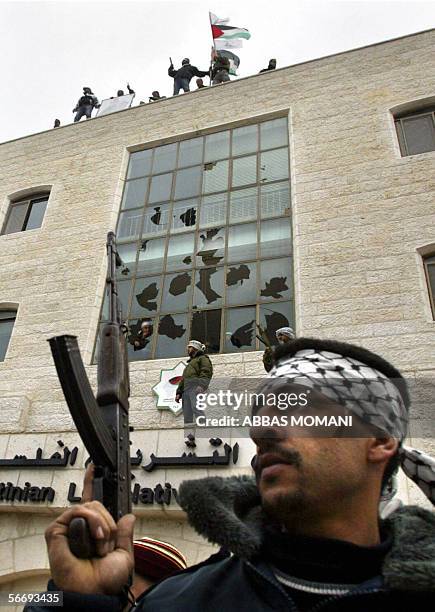 Palestinian Fatah members tot their rifles as gunmen erect a Palestinian flag and a Fatah banner on the Palestinian Legislative Council building, 28...