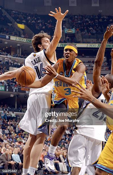 Chris Paul of the New Orleans/Oklahoma City Hornets drives to the basket between Pau Gasol and Hakim Warrick of the Memphis Grizzlies during a game...