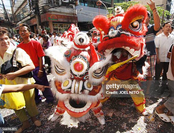 Filipinos watch performers carry out a dragon dance in streets of Chinatown in Manila 29 January 2006 in Chinese New Year celebrations ushering in...