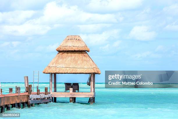 two chairs on dock under palapa, cancun, mexico - cancun fotografías e imágenes de stock