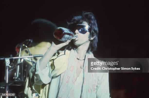 Guitarist Keith Richards having a drink while on stage during the Rolling Stones' 1975 Tour of the Americas.
