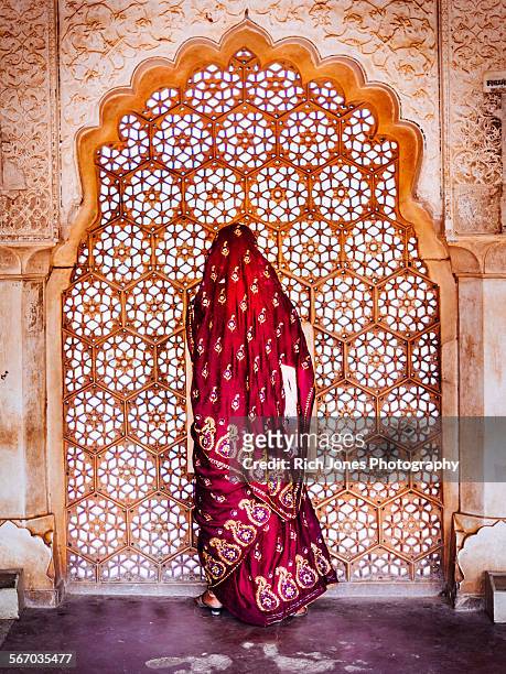 woman in sari at decorated window - rajasthani women stock-fotos und bilder