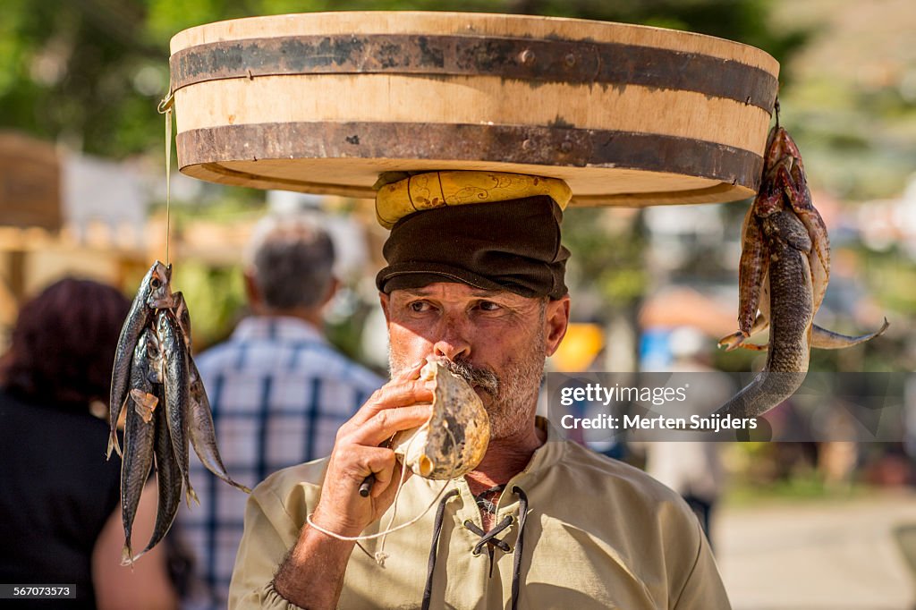 Fishmonger blowing seashell at festival