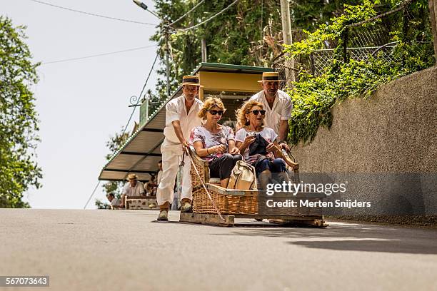 women in sledge being pushed downhill - madeira material stock-fotos und bilder