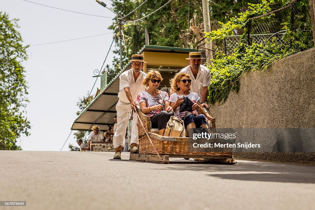 Women in sledge being pushed downhill
