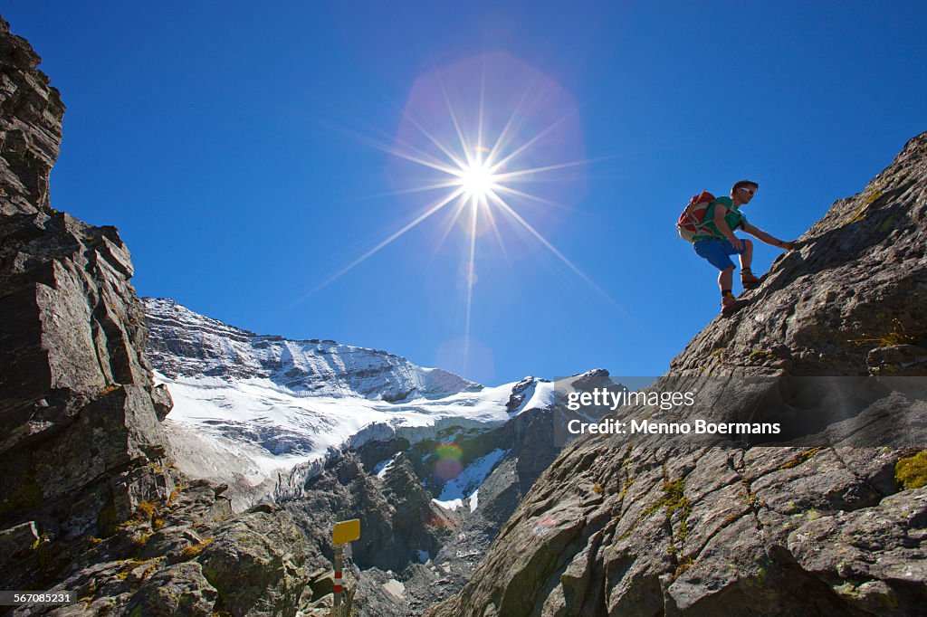 A male hiker climbs a rocky passage during the Glocknerrunde, a 7 stage trekking from Kaprun to Kals around the Grossglockner, the highest mountain of Austria.