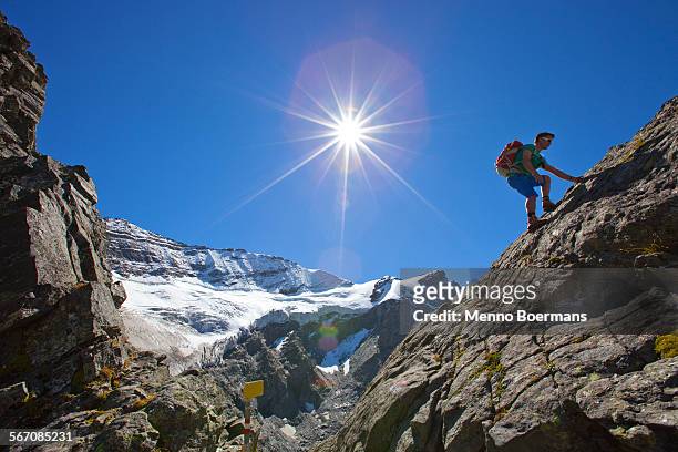a male hiker climbs a rocky passage during the glocknerrunde, a 7 stage trekking from kaprun to kals around the grossglockner, the highest mountain of austria. - grossglockner fotografías e imágenes de stock