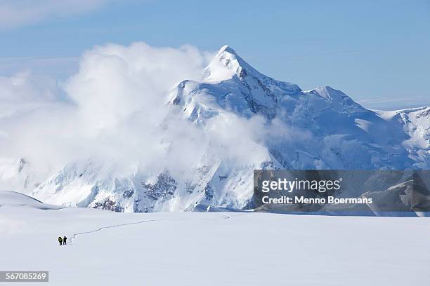 two mountaineers are crossing a glacier on mt. mckinley, alaska. mount hunter is in the background. - denali national park foto e immagini stock