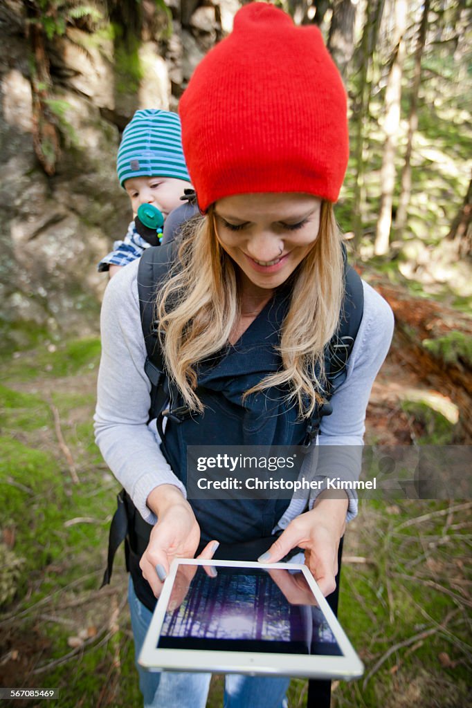 A young mother and her baby look down at a picture on a tablet.