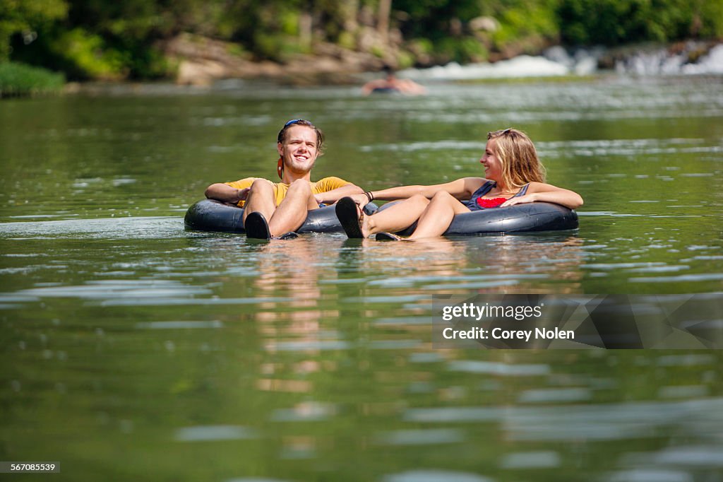 A young couple tubes down a river.