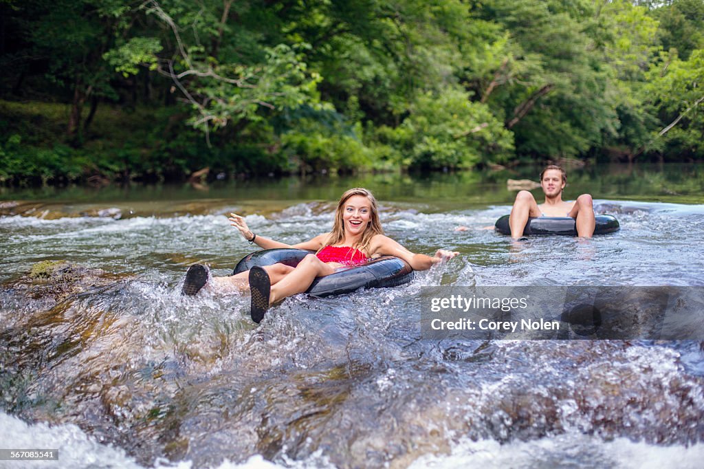 A young couple tubes down a river.