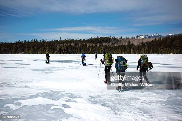 a group of winter hikers crossing a frozen pond - maine winter stock pictures, royalty-free photos & images