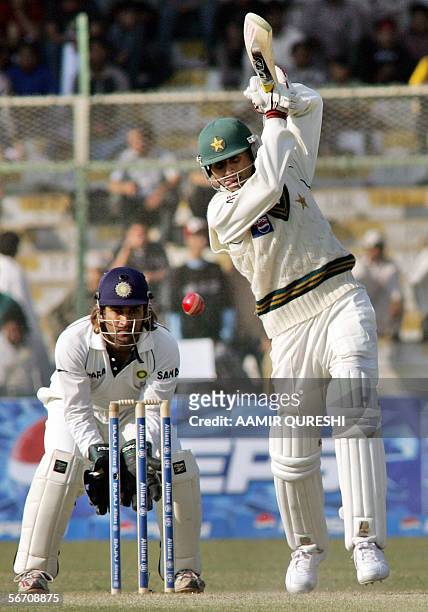 Pakistani cricketer Abdul Razzaq hits a shot as Indian wicketkeeper Mahendra Singh Dhoni looks on during the third day of the third and final Test...