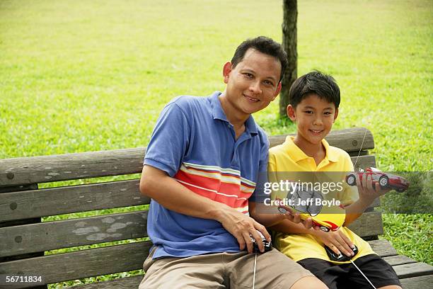 father and son holding remote control cars, smiling - remote control car games stockfoto's en -beelden