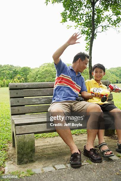 father and son holding remote control cars, smiling - remote control car games stockfoto's en -beelden