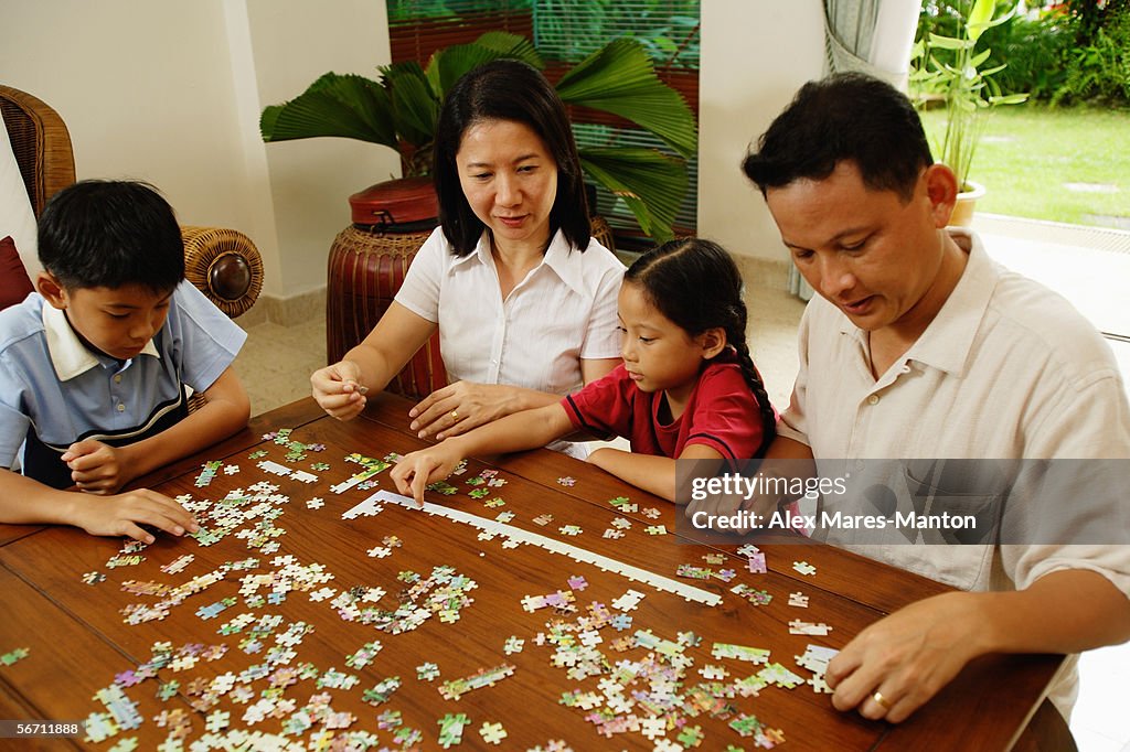 Family in living room working on jigsaw puzzle together