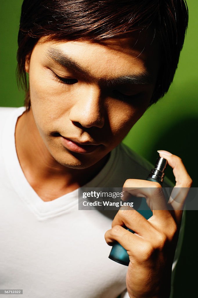 Young man holding bottle of perfume