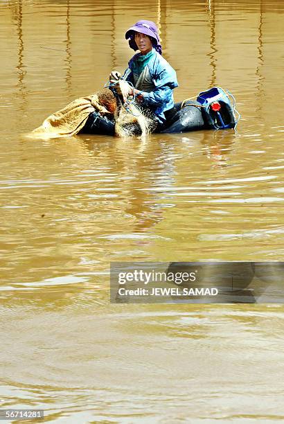 Man floats on a tube as he waits to spread his net for a catch on a canal beside a main street in Jakarta, 01 February 2006. Dozens of poor people...