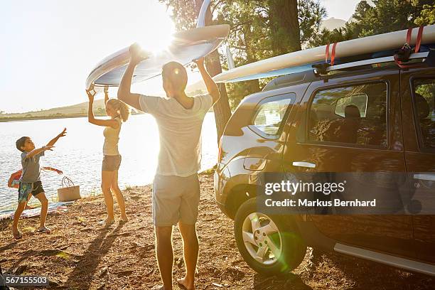 family unloading stand-up paddle board. - four people in car fotografías e imágenes de stock