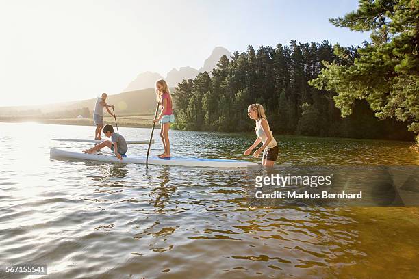 family does stand-up paddling. - paddleboarding team stock pictures, royalty-free photos & images